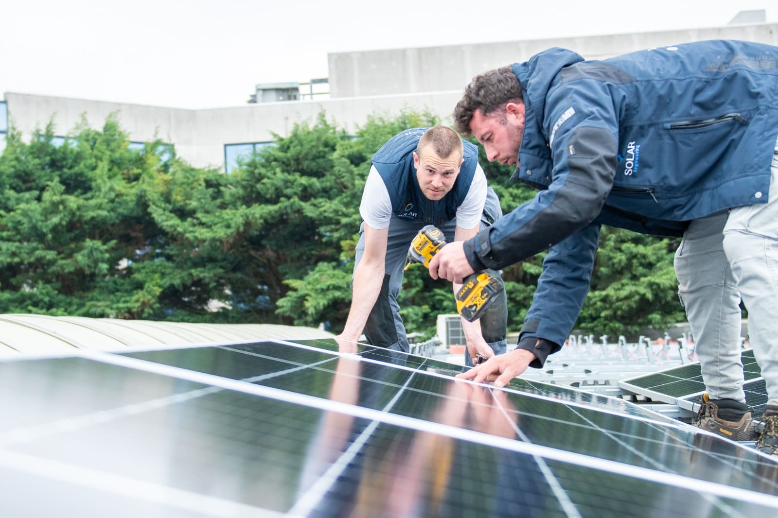 Technici van Solar Engineering installeren zonnepanelen op een dak om duurzame energieoplossingen te bieden.